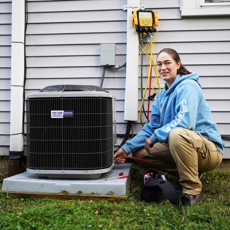 Technician kneeling beside outdoor AC unit with gauges